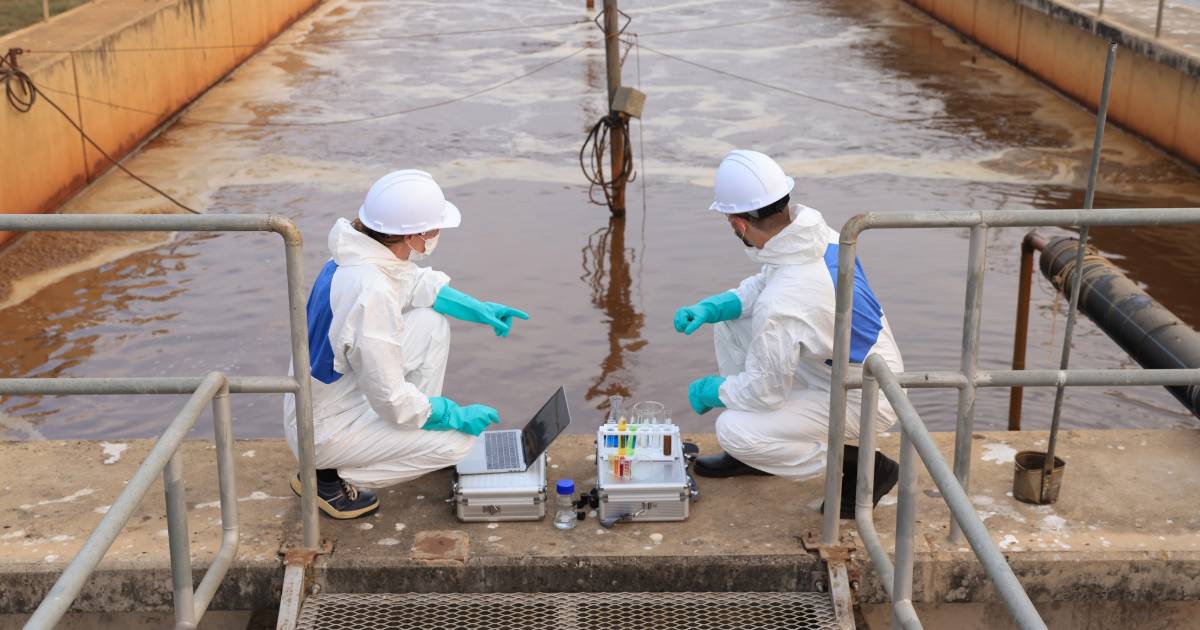 Two men conducting wastewater testing at a canal