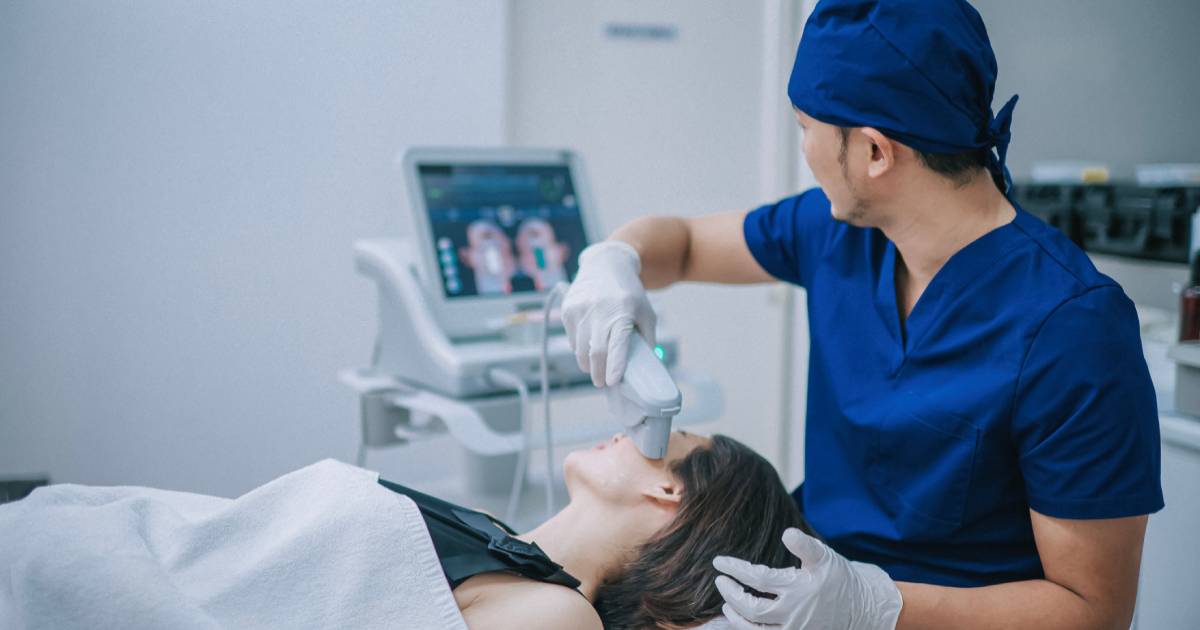 Male dermatologist using ultrasound on patient's face